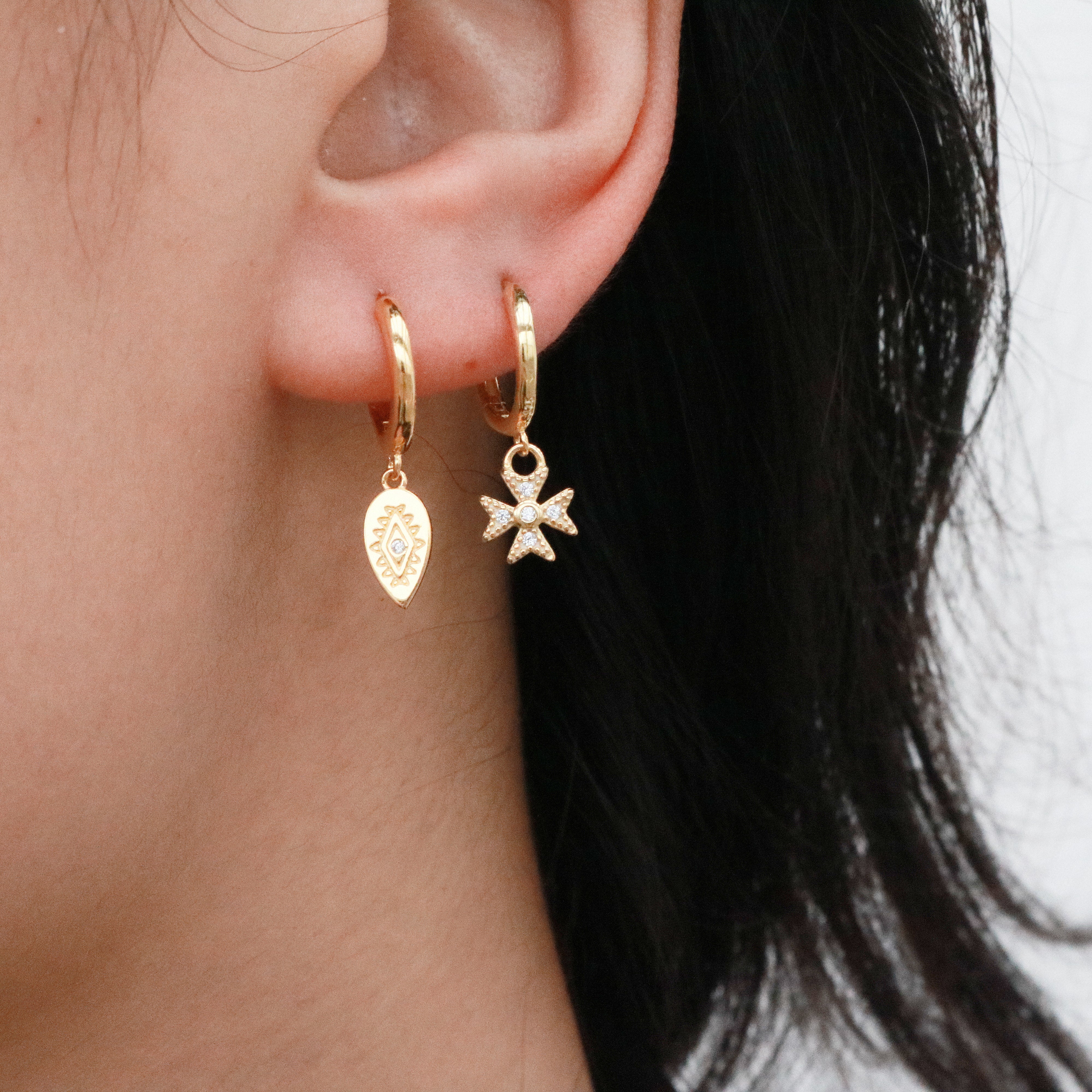 woman wearing two gold dangle hoop earrings