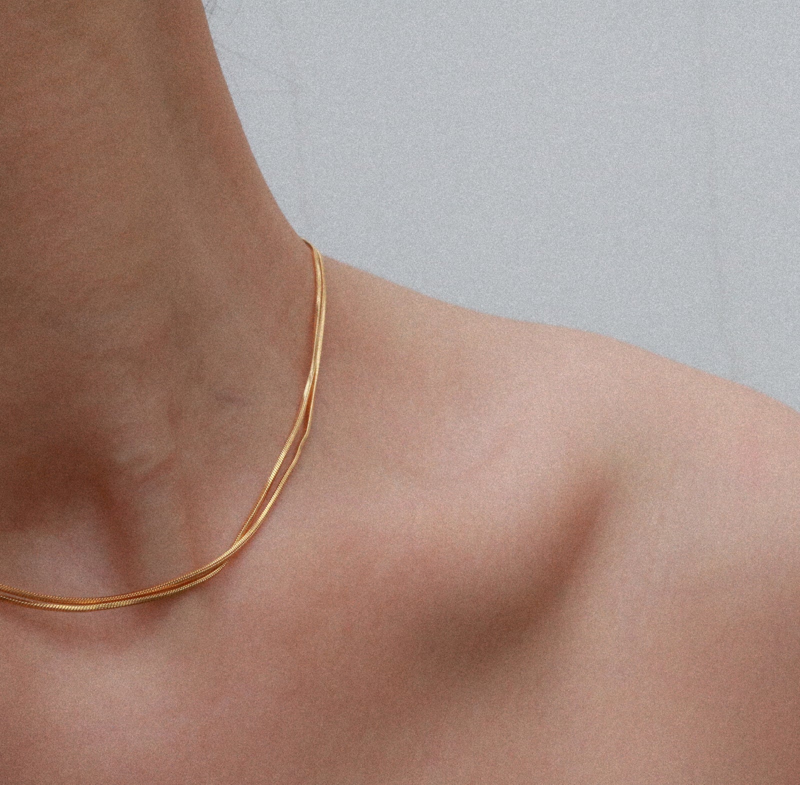 woman wearing two layers of gold chain necklace