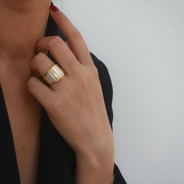 woman wearing a statement band ring which is gold plated and the ring features with striped mother of pearls