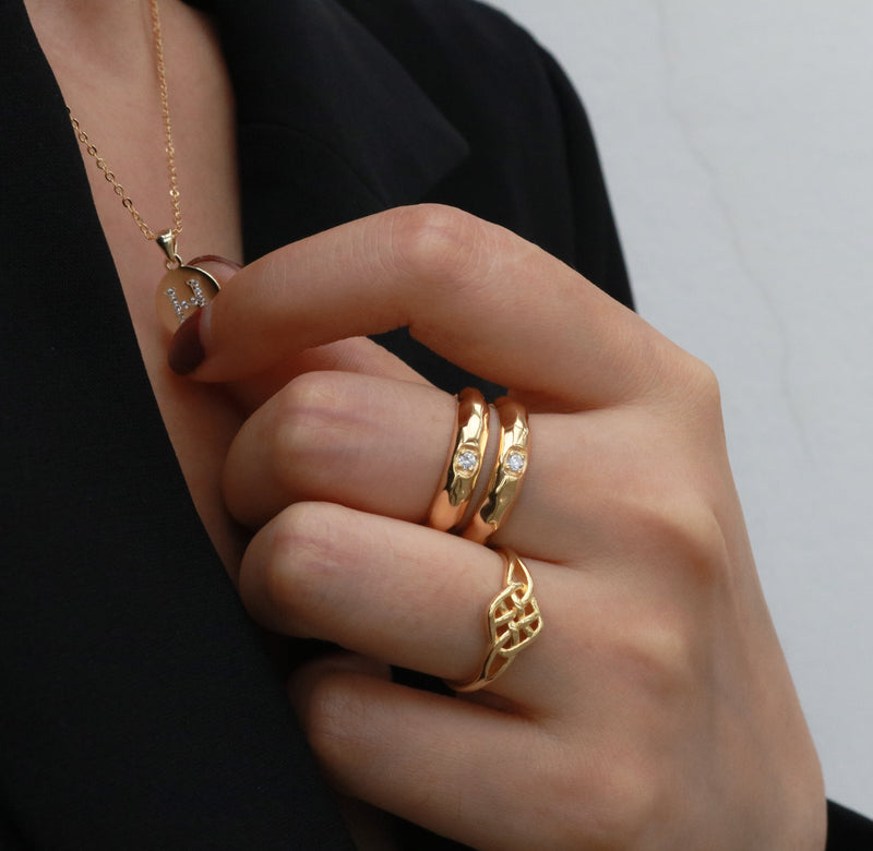 woman wearing gold rings and a letter necklace
